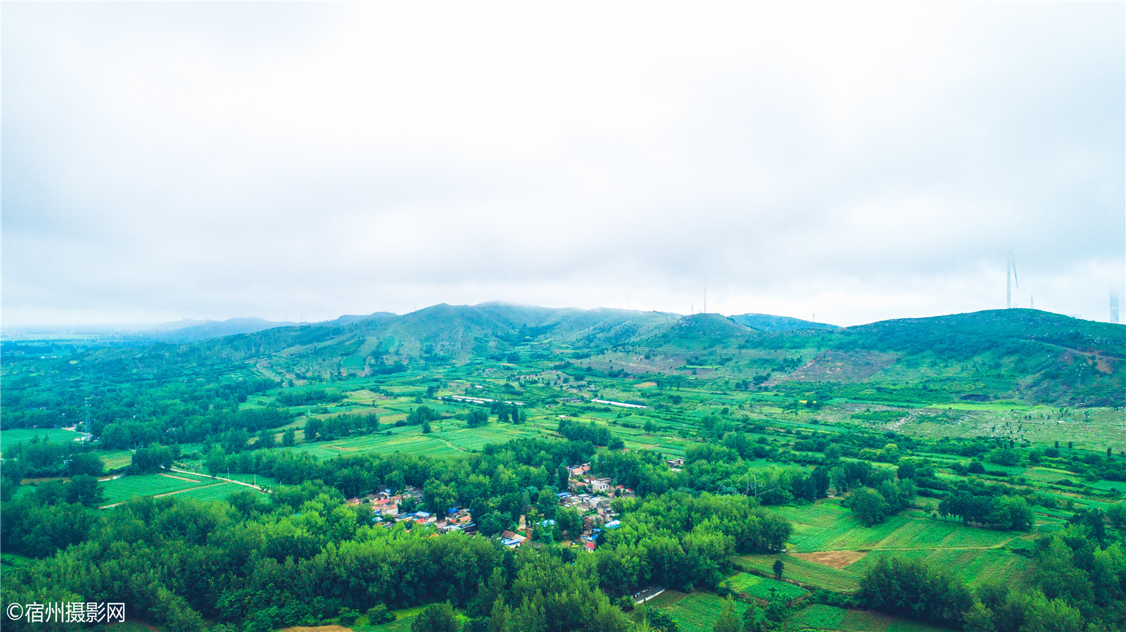 航拍符离牛口村绿茵环抱,远处雾锁山头.